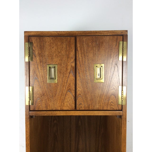 This mid century campaign style wall unit by Stanley Furniture features lighted area with glass shelf, upper cabinet with...
