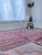 A large Moroccan rug hand-knotted in wool by Berber artisans, with a repeating diamond checkerboard across the full field...