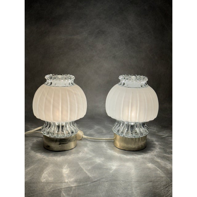A pair of Graewe night lamps from the 1960s featuring richly textured glass shades and gold-coloured plastic bases. The...