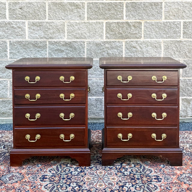 A pair of vintage Chippendale solid mahogany nightstands, each having four drawers with brass bail pulls and decorative...