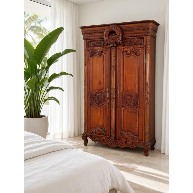 A striking French Provincial Louis XV-style armoire crafted in solid wood with elaborate carved detailing throughout. The...