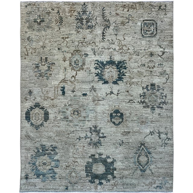 Large slate blue floral motifs alternate with smaller blossoms and fine taupe vines across this handmade Oushak rug. The...