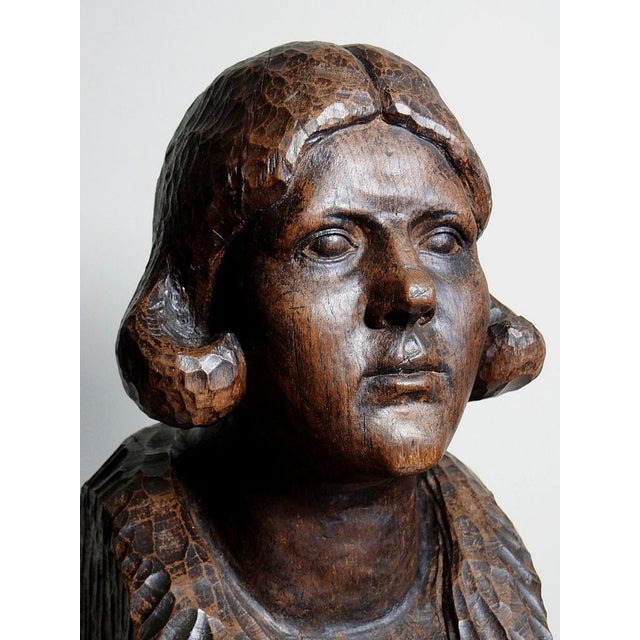A very imposing and superb bust of a woman in solid dark wood, carved from a single block with a gouge, dating from the...