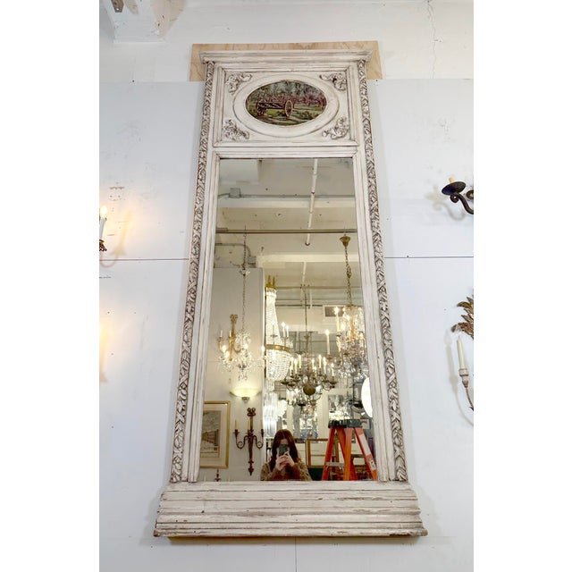 Antique Trumeau overmantel mirror with an upper panel that contains an oval framed artwork depicting a rustic outdoor...