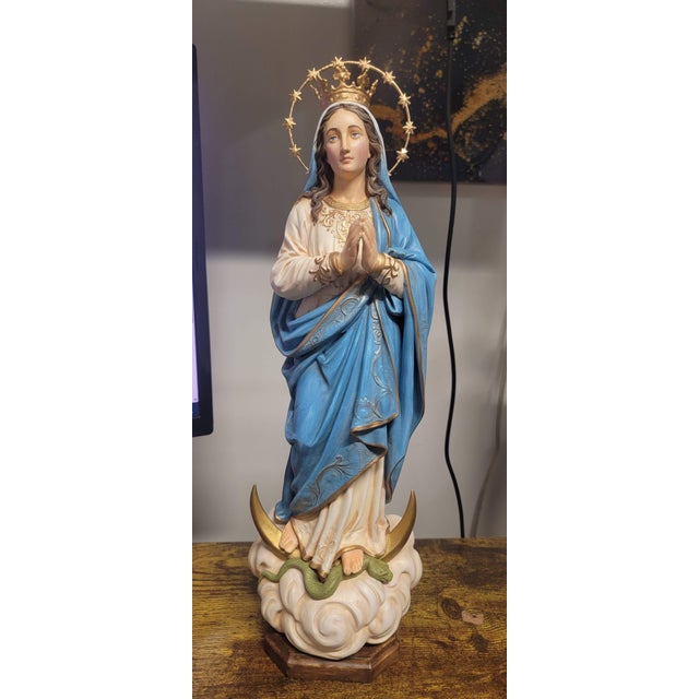 This Immaculate Conception figurine represents the Virgin Mary in a serene devotional posture, standing gracefully over a...