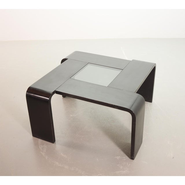 A stunning black lacquered square coffee table, constructed rom four bent plywood panels, seamlessly forming both tabletop...