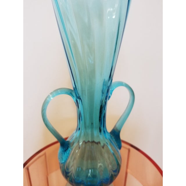 A luminous hand-blown art glass vase in a soft, watery blue with subtle tonal variation throughout the body. The...