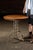 Round café-style table combining a cast metal base with a quarter-sawn oak top. The pedestal is formed from twin uprights...