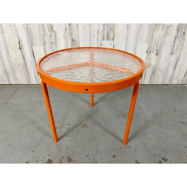 Round three legged side table newly powder coated in citrus orange. This table has the Peace symbol design where the three...