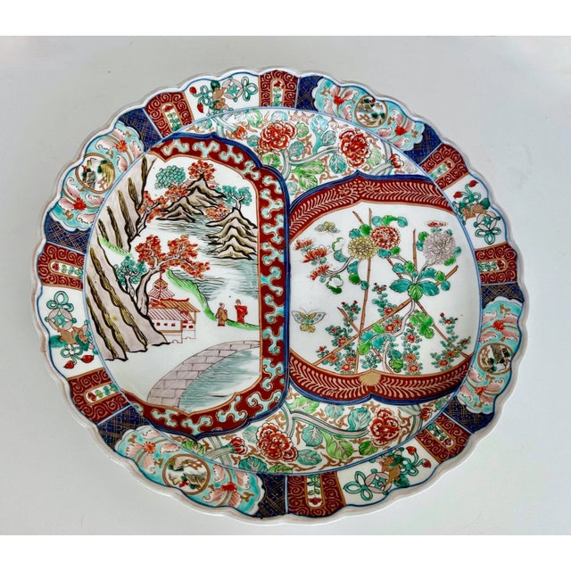 Hand painted porcelain Japanese Imari charger scallop edge plate with figures, buildings, trees, mountains, birds and...