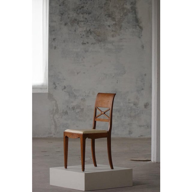 A graceful set of eight Danish dining chairs, crafted in oak circa 1920s–1930s. The design blends classical influences...