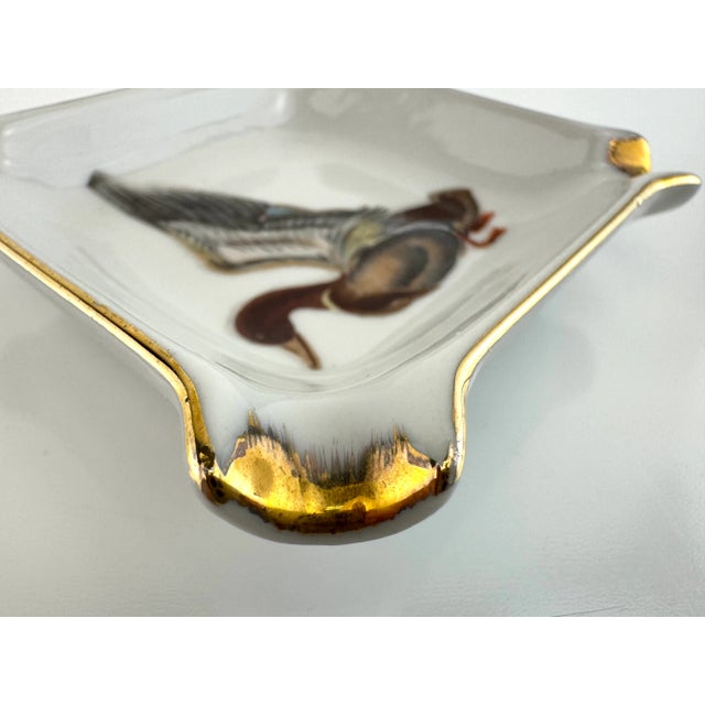 This petite vintage porcelain ashtray features a mid-century German design with a beautifully rendered duck in flight at...