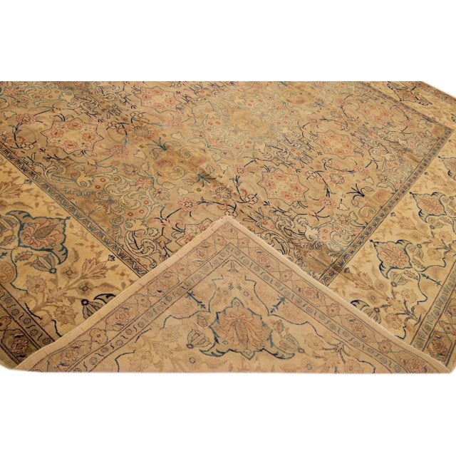 Beautiful antique Tabriz hand-knotted wool rug with a tan field. This Persian piece has orange, blue, and brown accents in...