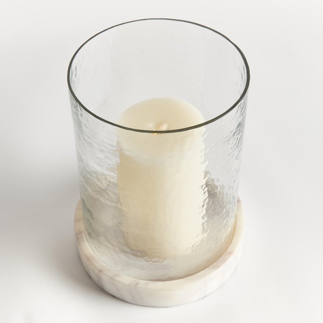 With a hammered glass vessel that sits inside a simply marble tray, this hurricane is decidedly modern. The hammered glass...