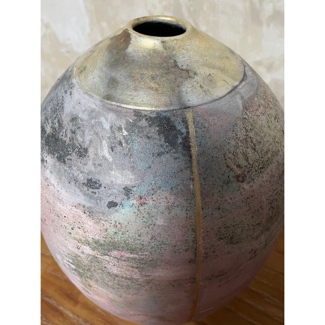 A nicely done raku studio pottery vessel in iridescent pastel colors with gold stripes running vertically. Signed "Albert."