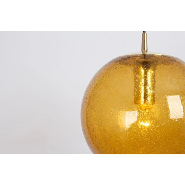 A special round dark yellow glass pendant designed by peill & putzler, manufactured in germany, circa 1970s. High quality...