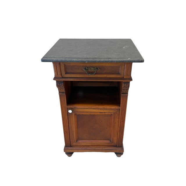This antique Victorian solid walnut bedside table or nightstand has a black marble top and drawer over an internal shelf....