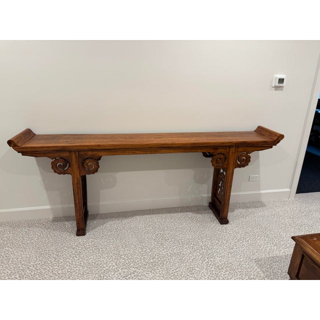 A beautifully hand-carved Chinese altar console table crafted in solid elm with traditional cloud-scroll detailing. The...