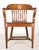 Vintage banker chair made of wood in a dark tone stain. It features a slatted back, curved arms, a contoured seat, and...