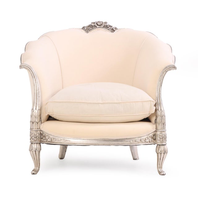 A lovely pair of carved wood lounge chairs executed in the Louis XV style, highlighted by central floral carved crests and...