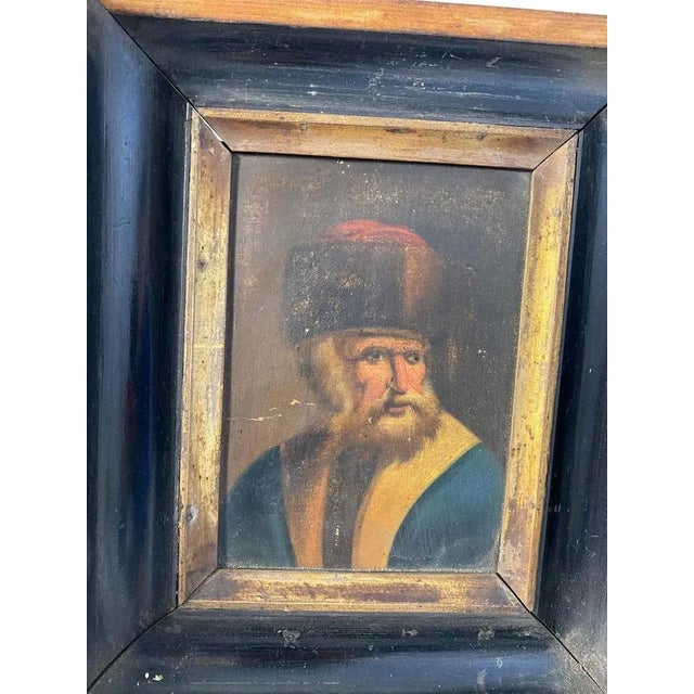 A rustic framed picture of what is likely a rabbi posing for a portrait. There is a lighter colored wooden inner frame...