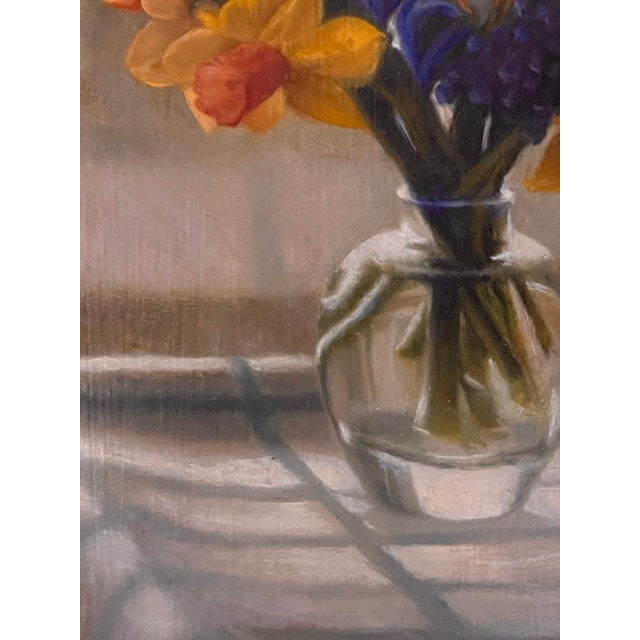 This artwork captures a serene moment with a vase of vibrant spring flowers resting on a textured tablecloth, illuminated...