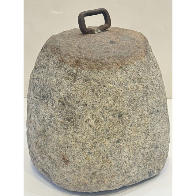 A hand-hewn English tethering stone of granite with an iron loop handle from the 19th century, used as a farm weight or...