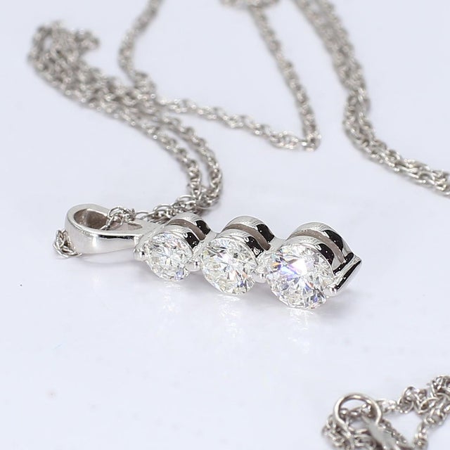 This is a clean looking three-stone diamond and white gold necklace with a chain included. Stone Info: 3x - VS2/E Diamonds...