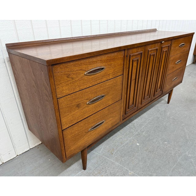 This listing is for a Mid-Century Modern Broyhill Sculptra Walnut 9-Drawer Dresser. Featuring a straight line design,...
