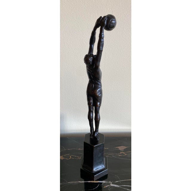 An Art Deco bronze with a rich chocolate brown patina of a figure of a goalkeeper. The figure is stretching up to parry...