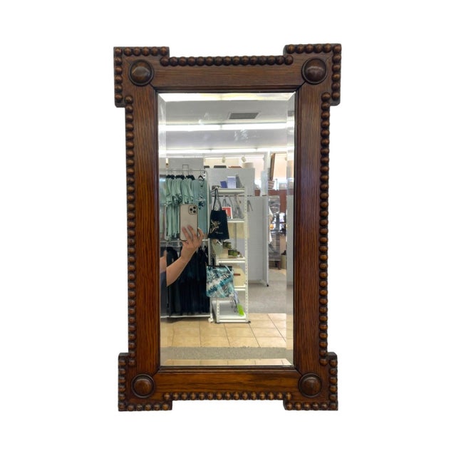 This antique rectangular wall mirror features a darkly stained quartersawn oak frame characterized by tight bobbin or...