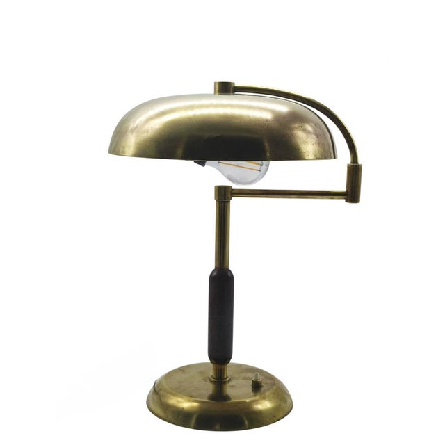 Brass desk lamp by Maison Desny featuring elegant, geometric lines and a minimalist design. It has a brass base and stem...