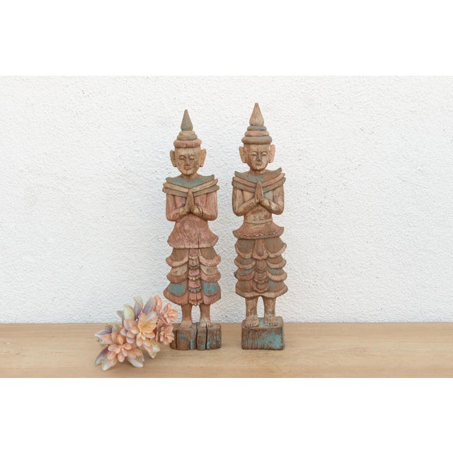 A rare and harmonious pair of antique Burmese folk carvings, representing celestial attendants offering respect. Standing...