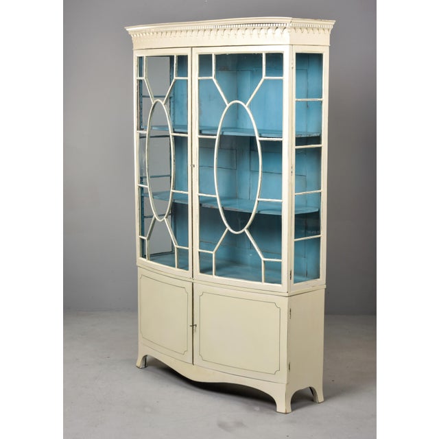 This English display cabinet follows the Hepplewhite tradition in two parts, both featuring a bow-fronted form. The upper...