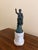 A classic Grand Tour style figure rendered in brass with a verdigris-toned finish, mounted on a substantial marble base....