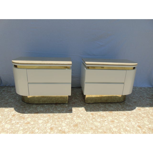 These night stands were designed by Steve Chase in the 1980s. They have travertine tops brass banding and they are white...