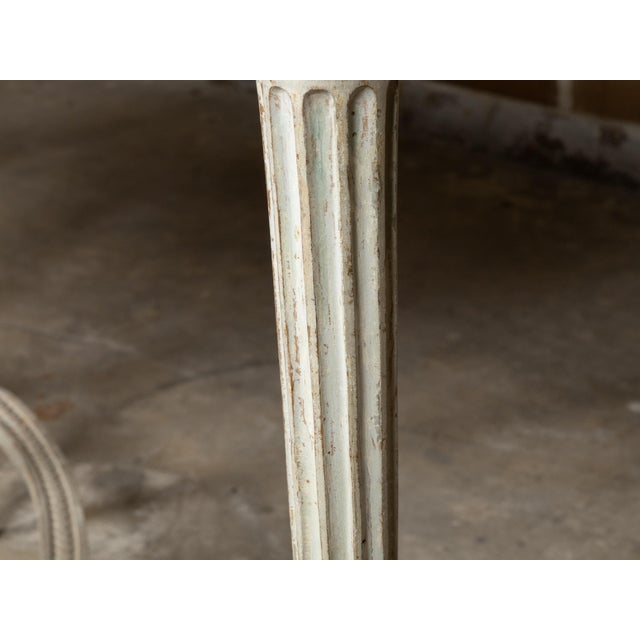 A pair of French Louis XVI period antique white painted console tables from the 18th century with marble tops, carved...