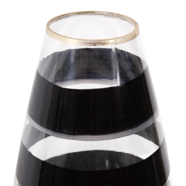 The Vector glass torpedo short vase features a hand painted black swirl pattern and a simple gold touch on the rim to...