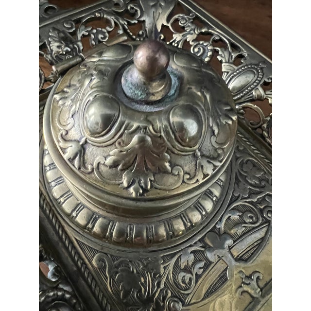 This antique ornate double inkwell stand is a striking example of late-19th to early-20th century desk décor, featuring...