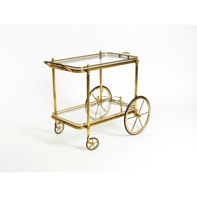 Beautiful 1960s serving or bar cart in neoclassical style crafted from brass with clear glass shelves. The upper glass...
