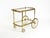 Beautiful 1960s serving or bar cart in neoclassical style crafted from brass with clear glass shelves. The upper glass...