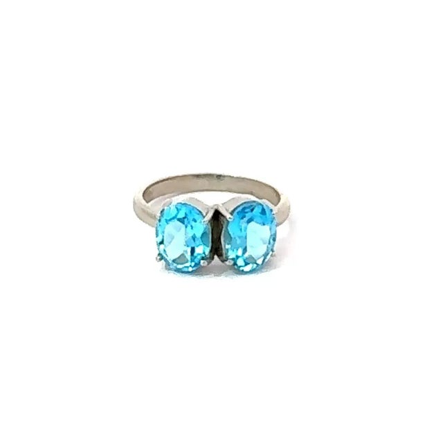 Crafted in 925 sterling silver, this exquisite ring highlights the brilliance of two oval-cut blue topaz gemstones. Each...