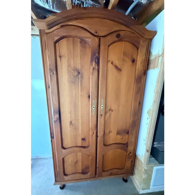 Traditional double-door solid pine armoire with classic arched bonnet top, raised panel doors and curved detailing. Warm...