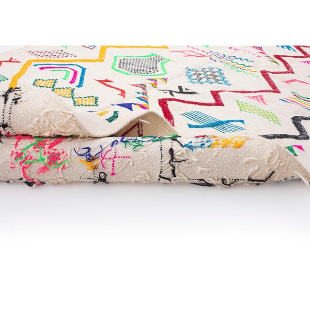 Vibrant handwoven wool rug featuring an array of lively geometric motifs in Fuchsia Pink, Emerald Green, Cobalt Blue, and...