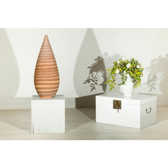 This tall late 20th-century artisan ceramic vase features a slender sculptural form with a rounded lower body, tapering...