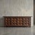 Deeply carved geometric motifs define the monumental facade of this 1960s Spanish sideboard, creating a rhythmic play of...