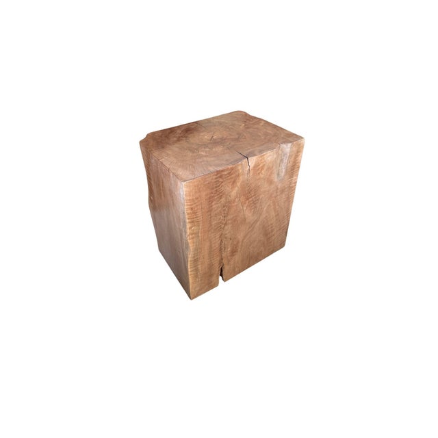 A sculptural side table carved from a single solid block of lychee wood, defined by its bold, monolithic presence and...