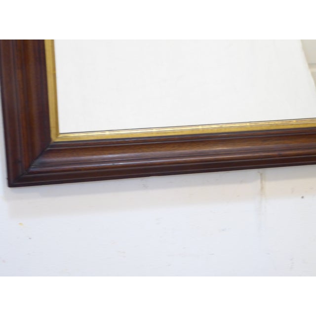 This curved top walnut mirror has a giltwood liner and measures30"H x 26"W.