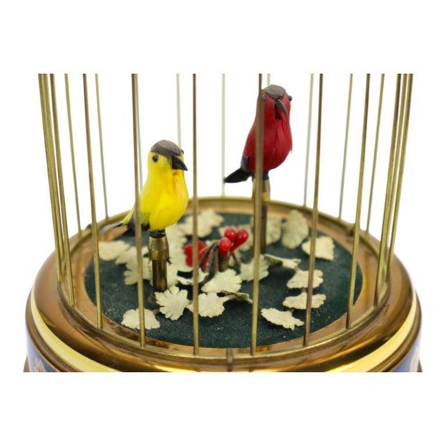 A Reuge Swiss singing-bird cage music automaton, circa 1910. The domed brass-tone cage houses two brightly colored birds...