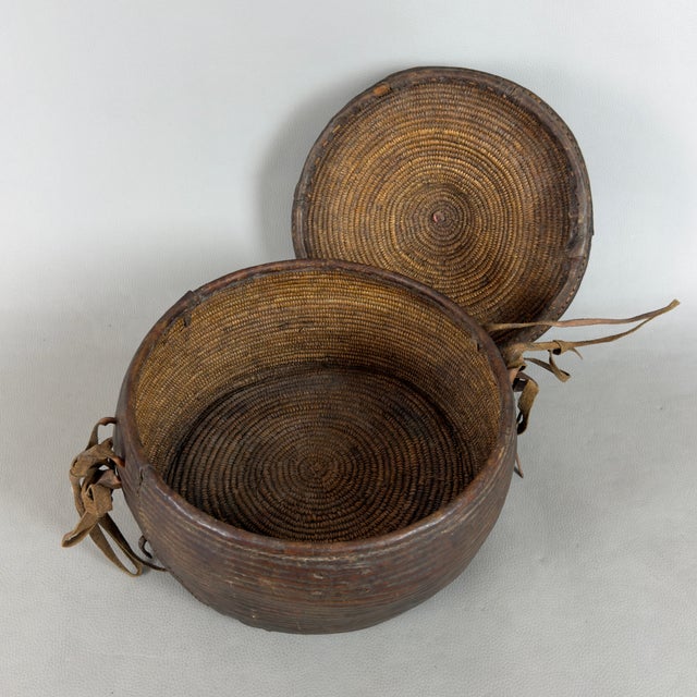 A rare and evocative nomadic storage basket with a lid and leather ties, attributed to traditional African craftsmanship...